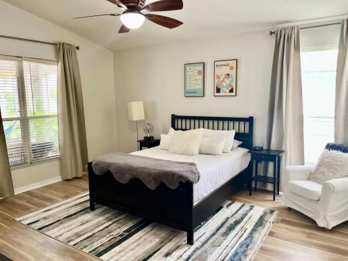 1 dormitorio con 1 cama, ventilador de techo y silla en Sandy Oasis 5 bedroom with Pool Sarasota Bradenton, en Bradenton