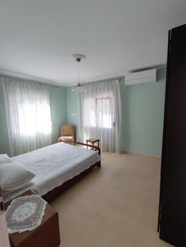 a bedroom with a bed and a chair and windows at kaite house in Kozani