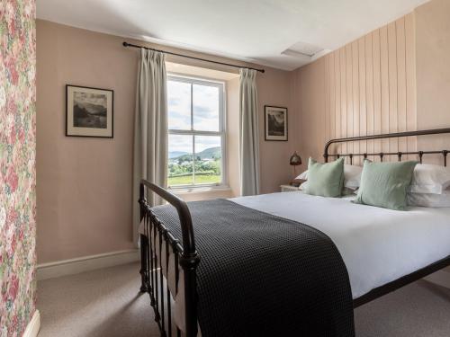 a bedroom with a large bed and a window at Stag Cottage in Penrith