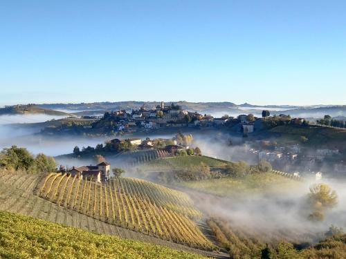 a village on a hill with fog in the valley at I Quattro Grappoli in Neive