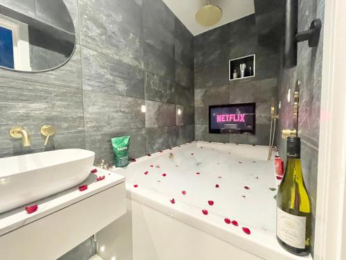 a bathroom with a tub with a sink and a bottle of wine at Cloud9 Guest House - by Coastline Retreats - FREE PARKING INCLUDED - 2 Bedroom self contained garden flat - Luxury 2 Person Bath, Netflix, Superfast Wifi in Bournemouth