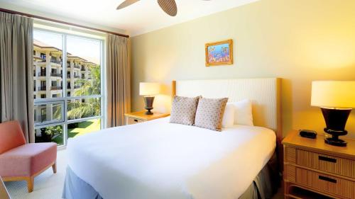 a bedroom with a white bed and a window at Honua Kai - Hokulani 414 in Lahaina