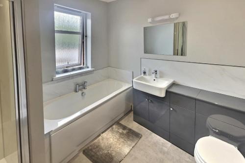 a bathroom with a tub and a sink and a toilet at Anne's Place in Boat of Garten