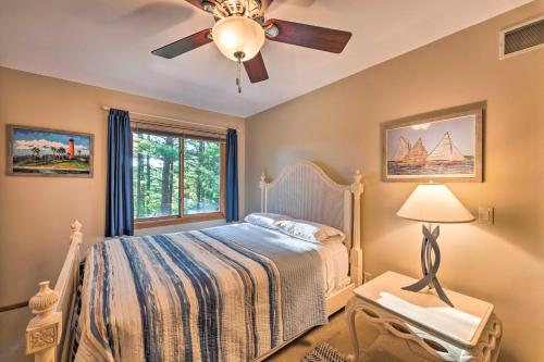 a bedroom with a bed with a ceiling fan and a window at Lake Geneva Getaway with Fire Pit Near Golf in Lake Geneva