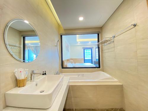 a bathroom with a sink and a tub and a mirror at FLC Luxury Apartment Quy Nhon in Quy Nhon