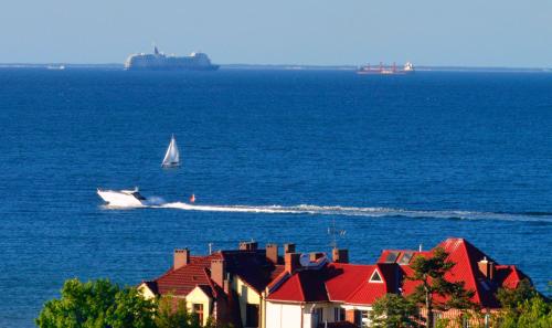 a boat in the water with a ship in the ocean at Pokoje przy plaży z widokiem na morze in Sopot