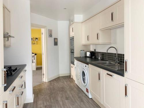 a kitchen with white cabinets and a washer and dryer at Park View Annexe 