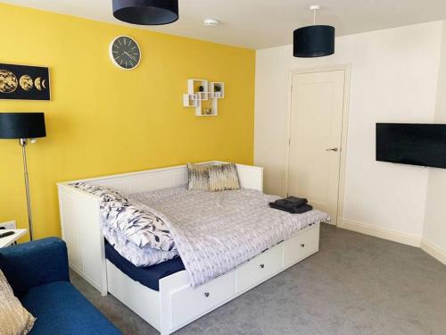 a bedroom with a white bed and a yellow wall at Park View Annexe 