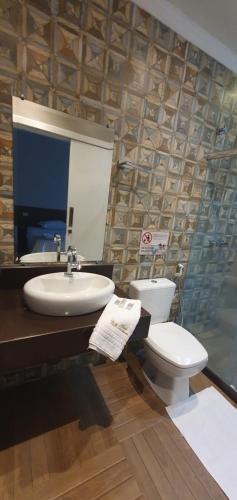 a bathroom with a toilet and a sink and a mirror at Pousada Dom Quixote in São João da Barra