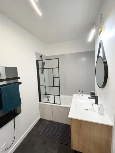 une salle de bain blanche avec un lavabo et un miroir dans l'établissement Deux pièces cosy à La Croisette, à Carrières-sous-Poissy
