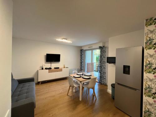 a kitchen and living room with a table and a couch at Deux pièces cosy à La Croisette in Carrières-sous-Poissy