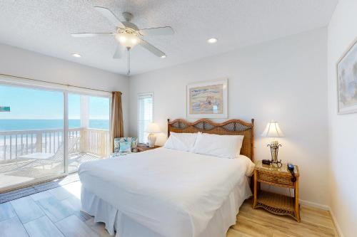 a bedroom with a white bed and a balcony at Beach Boy in St. George Island