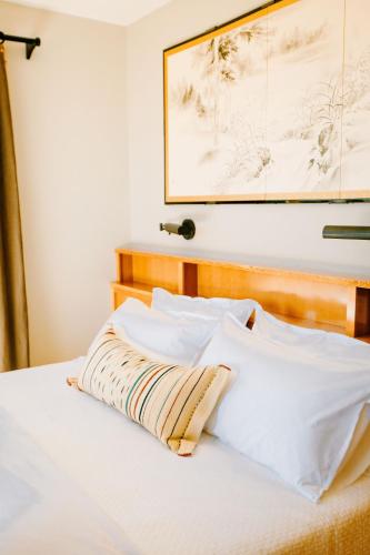 a bed with white pillows and a picture on the wall at Sakura Ridge Farm & Lodge in Hood River