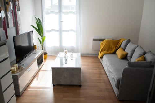 a living room with a couch and a tv at Lorraine in Mantes-la-Jolie