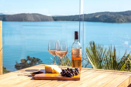 a bottle of wine and two glasses on a table at Palms on Kennedy Point - Stay Waiheke in Te Whau Bay
