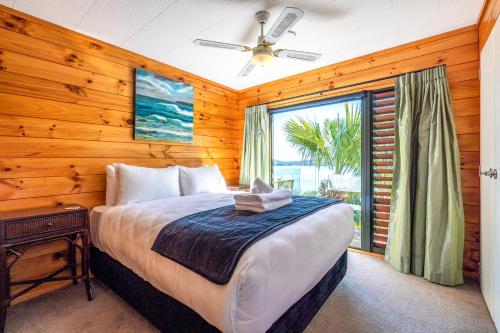 um quarto com uma cama e uma grande janela em Palms on Kennedy Point em Te Whau Bay