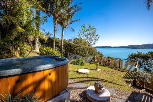 a hot tub in a yard with a view of the water at Palms on Kennedy Point - Stay Waiheke in Te Whau Bay