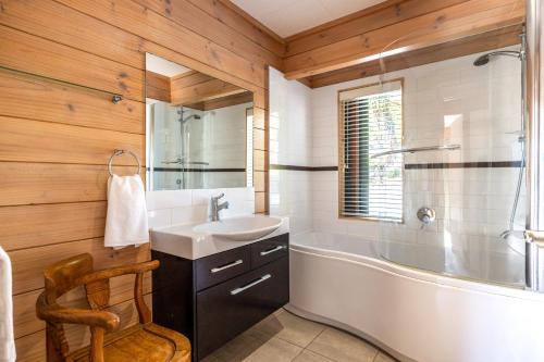 a bathroom with a white tub and a sink and a tubermott at Palms on Kennedy Point in Te Whau Bay