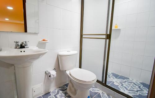 a bathroom with a toilet and a sink and a shower at Hotel Toledo Plaza in Armenia