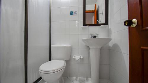 a white bathroom with a toilet and a sink at Hotel Toledo Plaza in Armenia