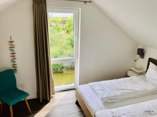 a bedroom with a bed and a large window at Familienhaus an der Nordsee - Sauna - Kamin - Südterrasse direkt über dem Wasser in Wangerland