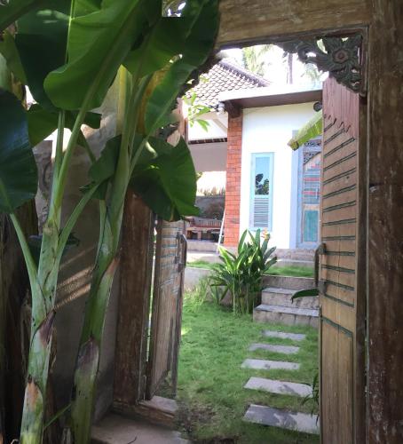 an open door to a garden with a plant at Pranajaya loka villa in Tejakula