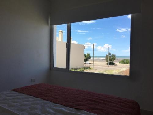 een slaapkamer met een raam met uitzicht op het strand bij COMPLEJO LAVANDAS in Balneario El Condor