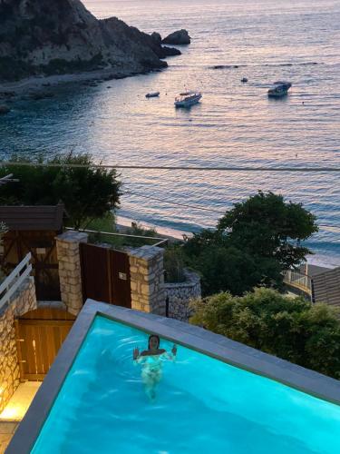 a person in a swimming pool with a view of the ocean at Caltabania Suites in Agios Nikitas