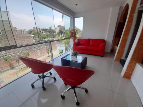 a living room with a red couch and a red chair at CasaHotel Jockey Plaza Mall in Lima