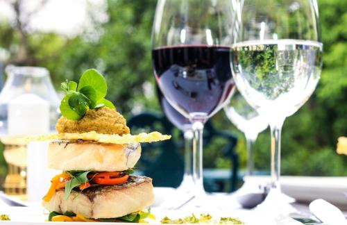 a sandwich on a table with two glasses of wine at Budmarsh Country Lodge in Magaliesburg