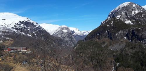 a snow covered mountain range with a building in the foreground at Stalheim Fjord og Fjellhytter in Stalheim