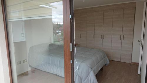 ein Schlafzimmer mit einem Bett und einer Glasschiebetür in der Unterkunft Departamento Nueva Villarrica in Villarrica