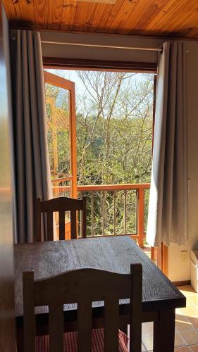 einem Holztisch und einem Stuhl vor einem großen Fenster in der Unterkunft Caminho do Sol in Monte Verde