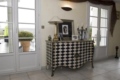 a table with a lamp on it in a room with windows at B&B Le Vert Galant in Normanville