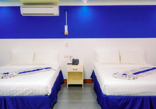 two beds in a room with a blue wall at Santiago Cove Hotel and Restaurant in Santiago