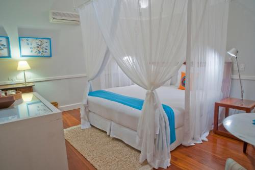 a bedroom with a canopy bed with white curtains at Casa Turquesa - Maison D´Hôtes in Paraty