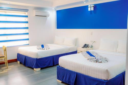two beds in a room with a large screen at Santiago Cove Hotel and Restaurant in Santiago
