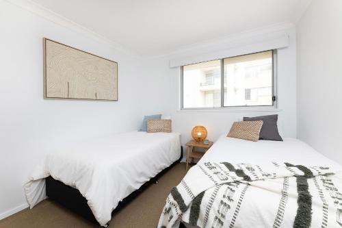 two beds in a room with white walls and windows at El Sandi, Unit 10, 14-18 North Street in Forster