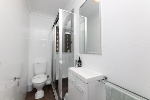 La salle de bains blanche est pourvue de toilettes et d'un lavabo. dans l'établissement El Sandi, Unit 10, 14-18 North Street, à Forster