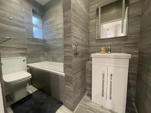 a bathroom with a toilet and a tub and a sink at Coast View Professional Let in Whitley Bay