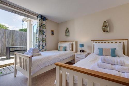 two beds in a bedroom with a balcony at Sowena in Carbis Bay