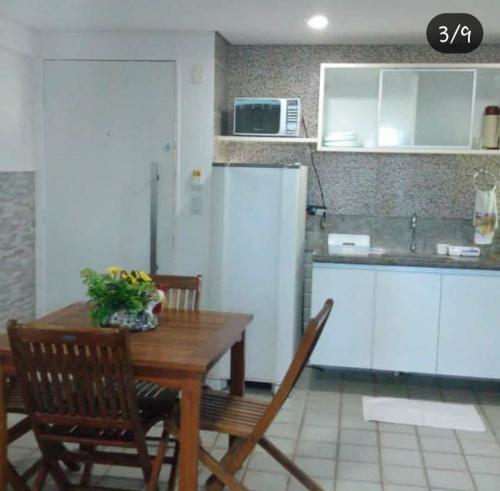 cocina con mesa de madera, sillas y encimera en Ancorar flat resort- porto de galinhas, en Porto de Galinhas