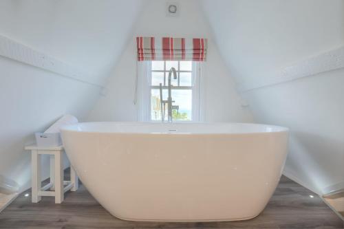 Una bañera blanca en un baño con ventana. en Sea Dream, en St Ives