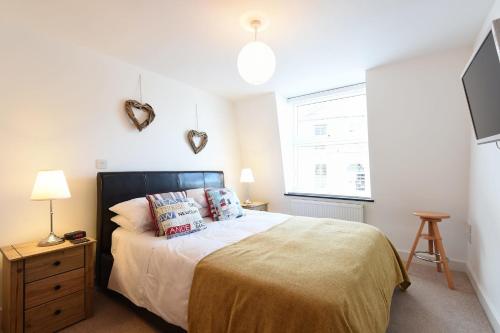 Un dormitorio con una cama y un televisor en la pared. en The Sail Loft, en St Ives