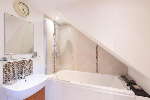 Un baño blanco con lavabo y bañera. en The Sail Loft, en St Ives