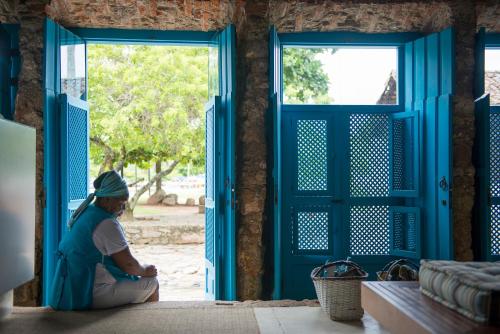 a woman sitting on the floor in front of doors at Casa Turquesa - Maison D´Hôtes in Paraty