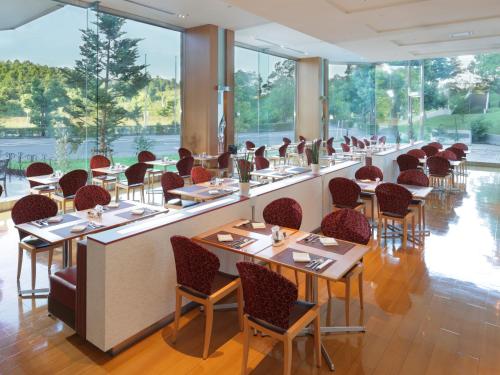 a restaurant with tables and chairs and windows at ANA Crowne Plaza Narita, an IHG Hotel in Narita