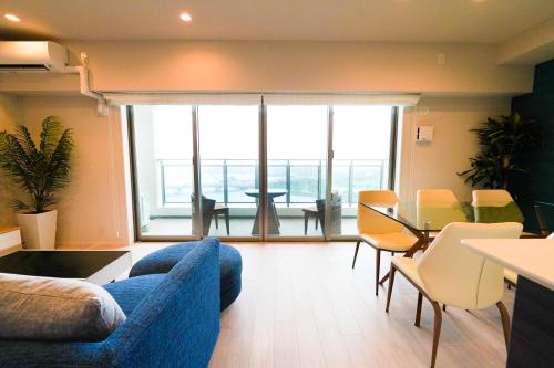 a living room with a blue couch and a table with chairs at Branchera Naha 1102 in Naha