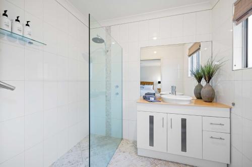 a bathroom with a glass shower and a sink at Riverside Breeze - luxury family retreat with pool in Port Macquarie