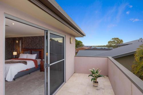a bedroom on the balcony of a house at Riverside Breeze - luxury family retreat with pool in Port Macquarie